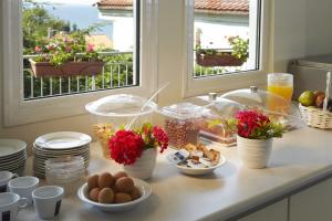 um balcão de cozinha com alimentos para pequeno-almoço e flores em vasos em Hotel Alkyonis em Platamon