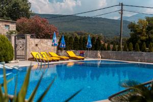 una piscina con sillas y sombrillas amarillas en Villa Ilijana, en Tivat