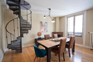 a dining room with a table and chairs and a spiral staircase at Vut carretas 21 in Madrid