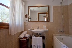 a bathroom with a sink and a tub and a mirror at Agroturisme Na Martina in Portopetro