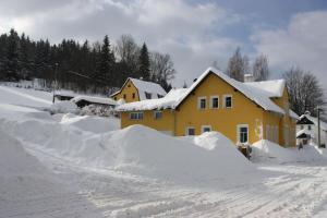 a yellow house is covered in snow at Apartmány Doma in Janov nad Nisou