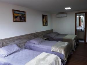 a room with three beds in a room at 100% Flats in Gramado