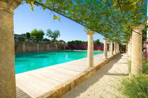 a swimming pool with a wooden boardwalk and trees at Rocco Forte Masseria Torre Maizza in Savelletri di Fasano