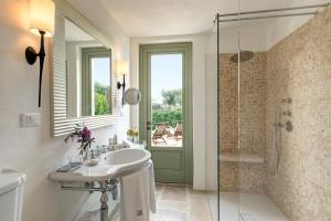 a bathroom with a sink and a glass shower at Rocco Forte Masseria Torre Maizza in Savelletri di Fasano
