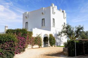 a white building with bushes and pink flowers at Rocco Forte Masseria Torre Maizza in Savelletri di Fasano