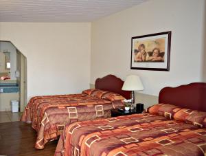 una habitación de hotel con 2 camas y una lámpara en Centre Suite Inns Motel, en Bonnyville