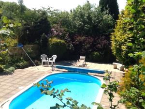 una piscina en un jardín con 2 sillas en Tudor Lodge, en Liskeard