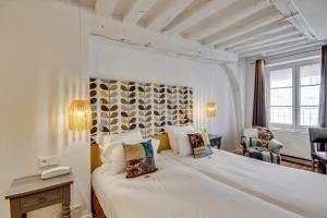 パリにあるホテル セーブル サン ジェルマンのベッドルーム1室(白い大型ベッド1台付)