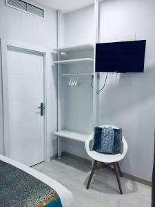 ein Schlafzimmer mit einem Bett und einem Stuhl und einem Fernseher in der Unterkunft Hostal Palacio Luna in Madrid