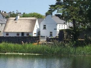 una casa junto a un cuerpo de agua con edificios en Lakeland House en Cong