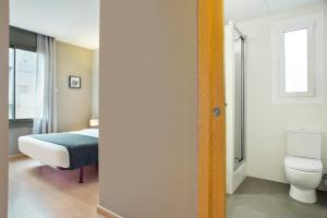 een slaapkamer met een bed, een toilet en een raam bij Bonavista Apartments - Pedrera in Barcelona