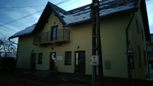una casa gialla con balcone e neve sul tetto di Casa Mindru a Topliţa