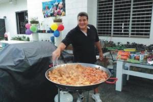 a man standing next to a large pan of food at Villa Vassallo in Ponce