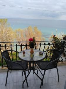 a table with a vase of flowers on a balcony at mare di zante "mare di levante" in Alikanas