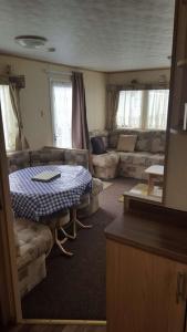 a living room with a table and a couch at 8 BERTH CARAVAN TP60 ON THE GOLDEN PALM CHAPEL ST LEONARD in Chapel Saint Leonards