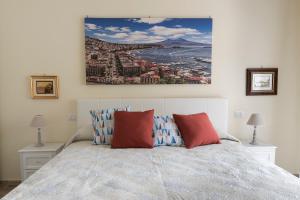 Un dormitorio con una cama con almohadas rojas y una pintura en la pared. en La maison de Julie, en Vico Equense