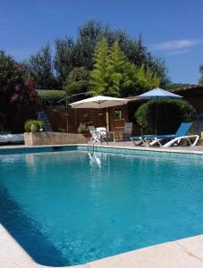 une grande piscine avec des chaises et des parasols dans l'établissement Domaine du Lac de la vallée, à La Roquette-sur-Siagne