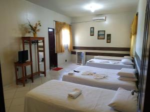 a hotel room with three beds and a television at hotel encontro das aguas in Santarém