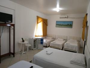 a room with three beds and a flat screen tv at hotel encontro das aguas in Santarém
