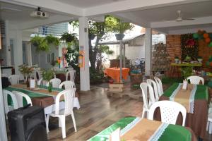 Hotel la Colina في Venadillo: مطعم بطاولات وكراسي بيضاء مع مفارش خضراء