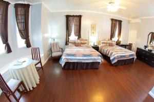 a bedroom with two beds and a table and chairs at The Great House Inn in Belize City +108 photos