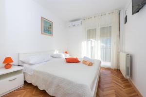 een witte slaapkamer met een bed en een raam bij Apartments Peričić in Podstrana