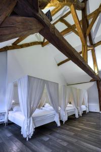 een rij bedden in een kamer met houten plafonds bij La Maison Blanche in Beaune