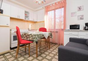 a kitchen with a table and two red chairs and a couch at Apartment Villa Olga in Poreč