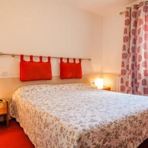 ein Schlafzimmer mit einem Bett mit roten Kissen darauf in der Unterkunft Logis Auberge Cigaloise in Saint-Hippolyte-du-Fort