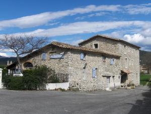 ein großes Steingebäude mit blauen Fenstern in der Unterkunft Logis Auberge Cigaloise in Saint-Hippolyte-du-Fort