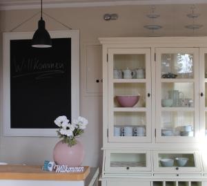 una cocina con un armario blanco con un jarrón de flores en Lütte Pension, en Egestorf