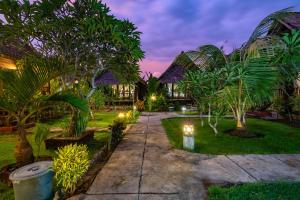 a garden with palm trees and lights at night at Sedok Jineng Villa in Nusa Lembongan