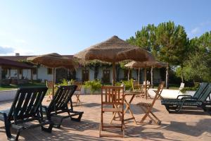 a group of chairs and tables with straw umbrellas at Casa de Campo Vale do Asno in Altura