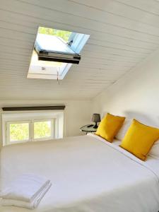 a bedroom with a large white bed with a skylight at WW Hostel & Suites in Coimbra