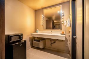 a bathroom with a sink and a mirror and a microwave at Crescent Bay Inn in Laguna Beach
