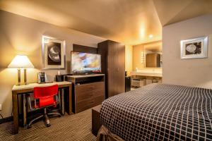 a hotel room with a bed and a desk and a television at Crescent Bay Inn in Laguna Beach