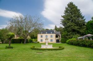 a garden with a fountain in front of a house at Le Petit Manoir de Vitrac in Vitrac