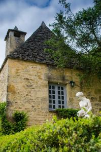 a stone building with a statue in front of it at Le Petit Manoir de Vitrac in Vitrac