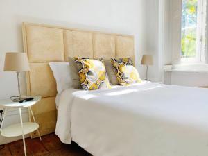a bedroom with a large white bed with pillows at WW Hostel & Suites in Coimbra