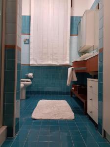 a blue tiled bathroom with a toilet and a rug at Residenza Annalisa in Torri di Quartesolo +9 photos
