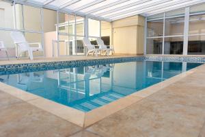 ein Schwimmbad mit weißen Stühlen und ein Schwimmbad in der Unterkunft Hotel Piren in Puerto Madryn