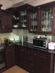 a kitchen with wooden cabinets and a microwave on a counter at Ivory Home Stay & Self-Catering Guest House in Ja-Ela