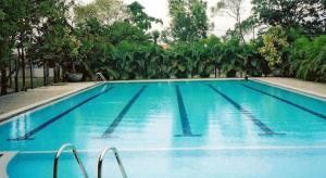 a large blue swimming pool with trees in the background at Ivory Home Stay & Self-Catering Guest House in Ja-Ela