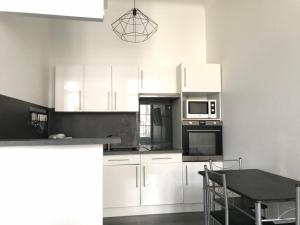 a kitchen with white cabinets and a table with chairs at Charme ancien & confort - cœur de ville in Auxerre