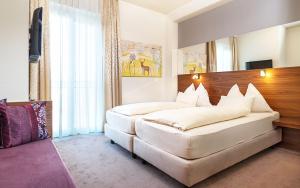 Schlafzimmer mit einem großen weißen Bett mit einem Kopfteil aus Holz in der Unterkunft Hotel Römerstube in Graz