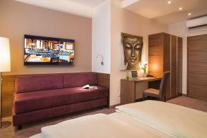a hotel room with a bed, couch and television at Hotel Römerstube in Graz