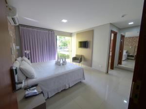 a bedroom with a white bed and a large window at Marruá Hotel in Bonito