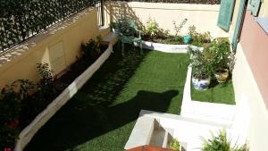 a small garden with grass and plants on the side of a building at Hotel Marcellin in Beaulieu-sur-Mer
