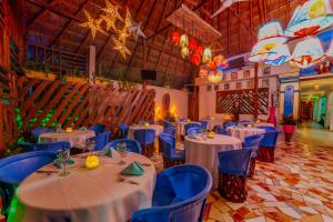 un salón de banquetes con mesas blancas y sillas azules en Mestizo Gallery en Tulum