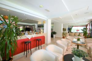 a waiting room with white chairs and a bar at Hotel De Amicis in Riccione